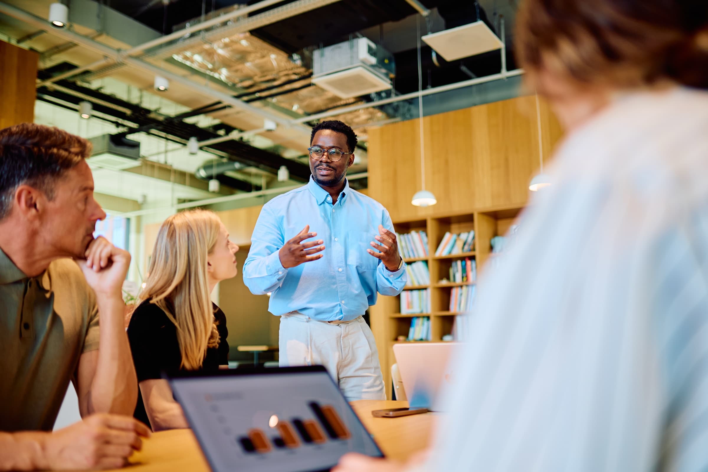 A leader presenting to colleagues around a table in a modern office